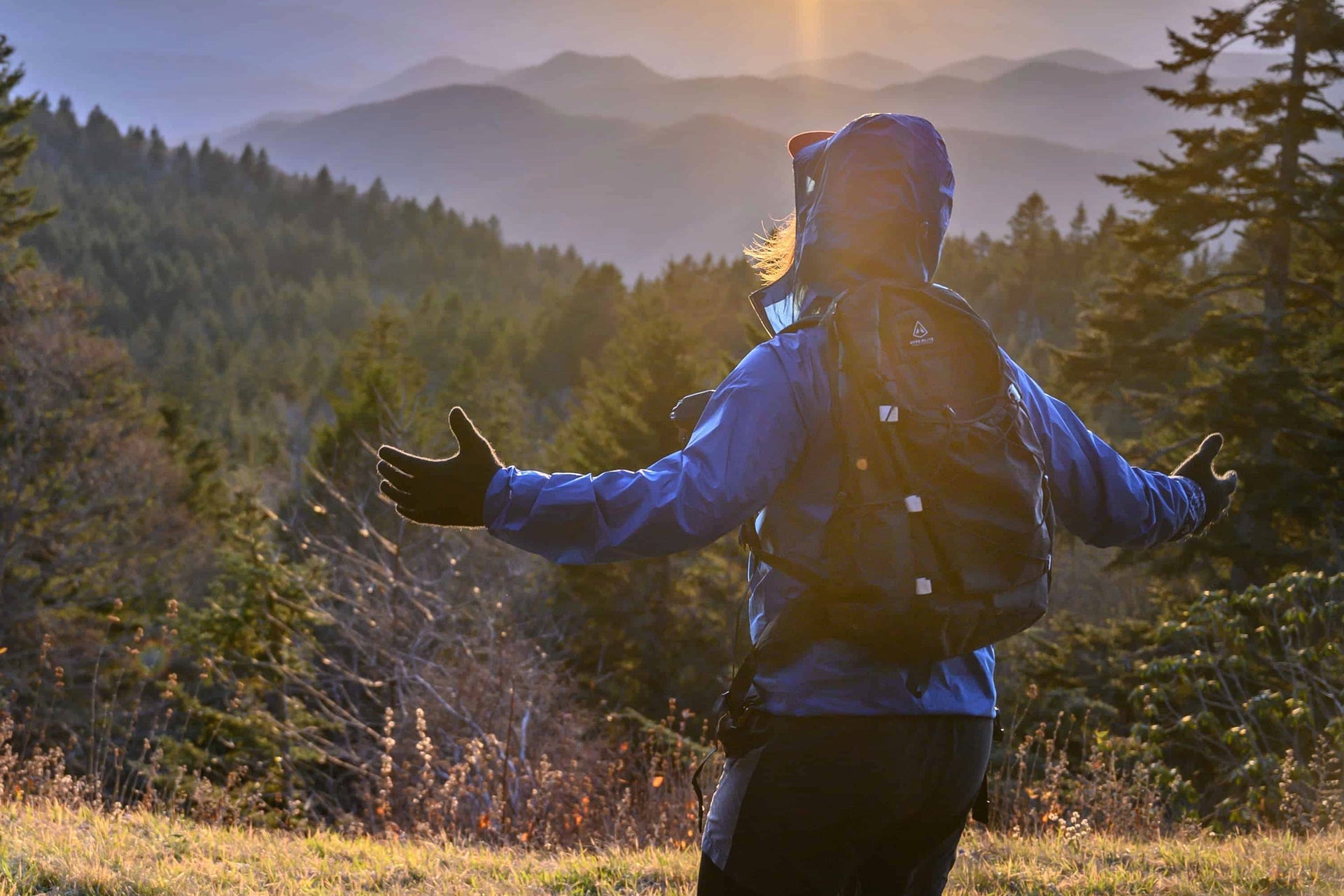 A woman hiking in the mountains with her arms outstretched.