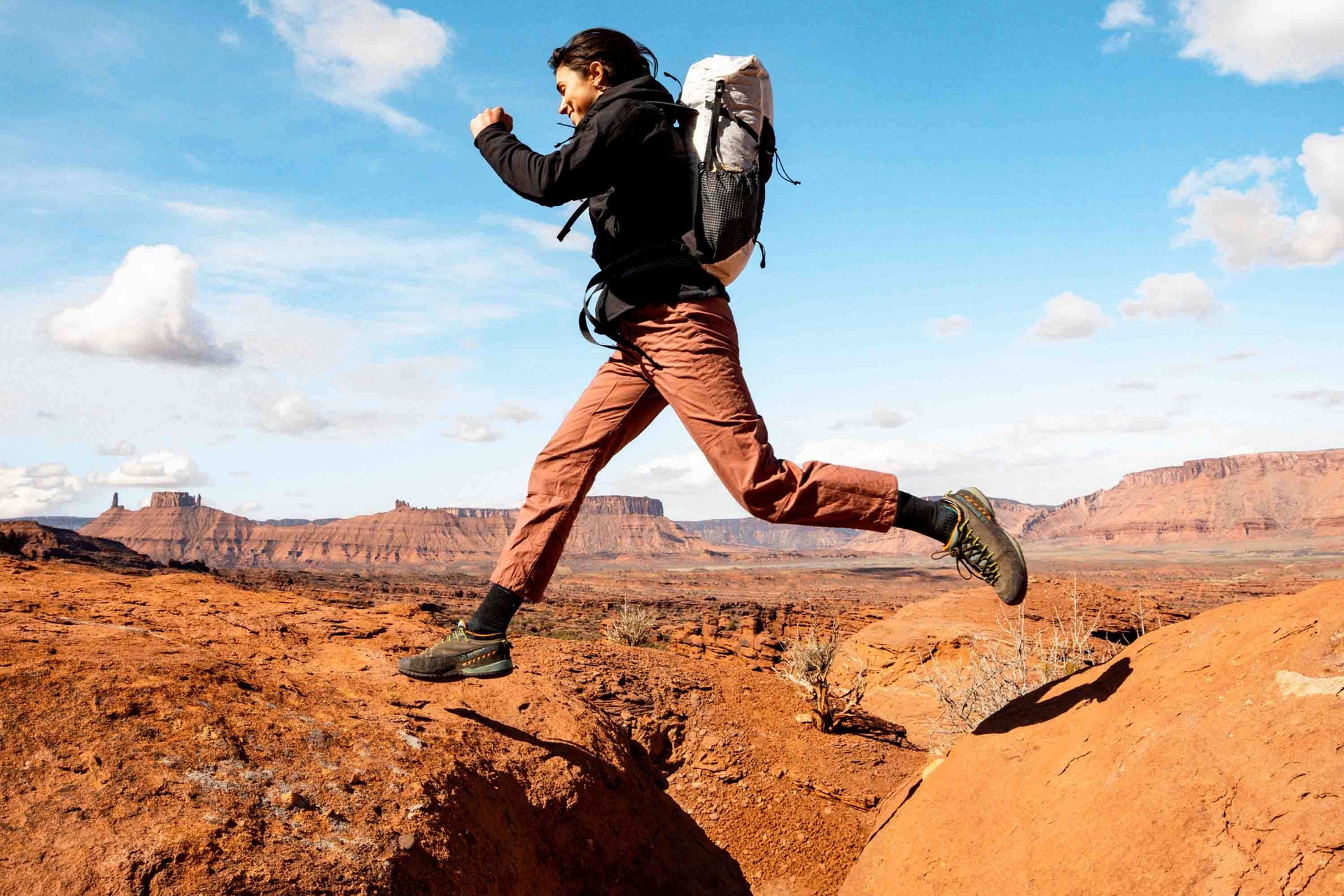 A woman is jumping over a rock in the desert.