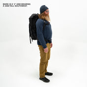 Male sporting a beard and showcasing the Black Southwest 55 backpack against a plain backdrop