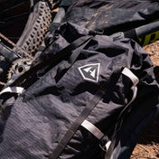 Front view of Hyperlite Mountain Gear's Porter 70 Pack in Black on top of a bike on the ground