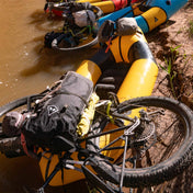 Hyperlite Mountain Gear's Porter 70 Pack in Black with a mountain bike on top of a kayak in a river