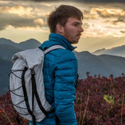 Hiker wearing Hyperlite Mountain Gear's Packs Summit 30 in White with mountains in the background